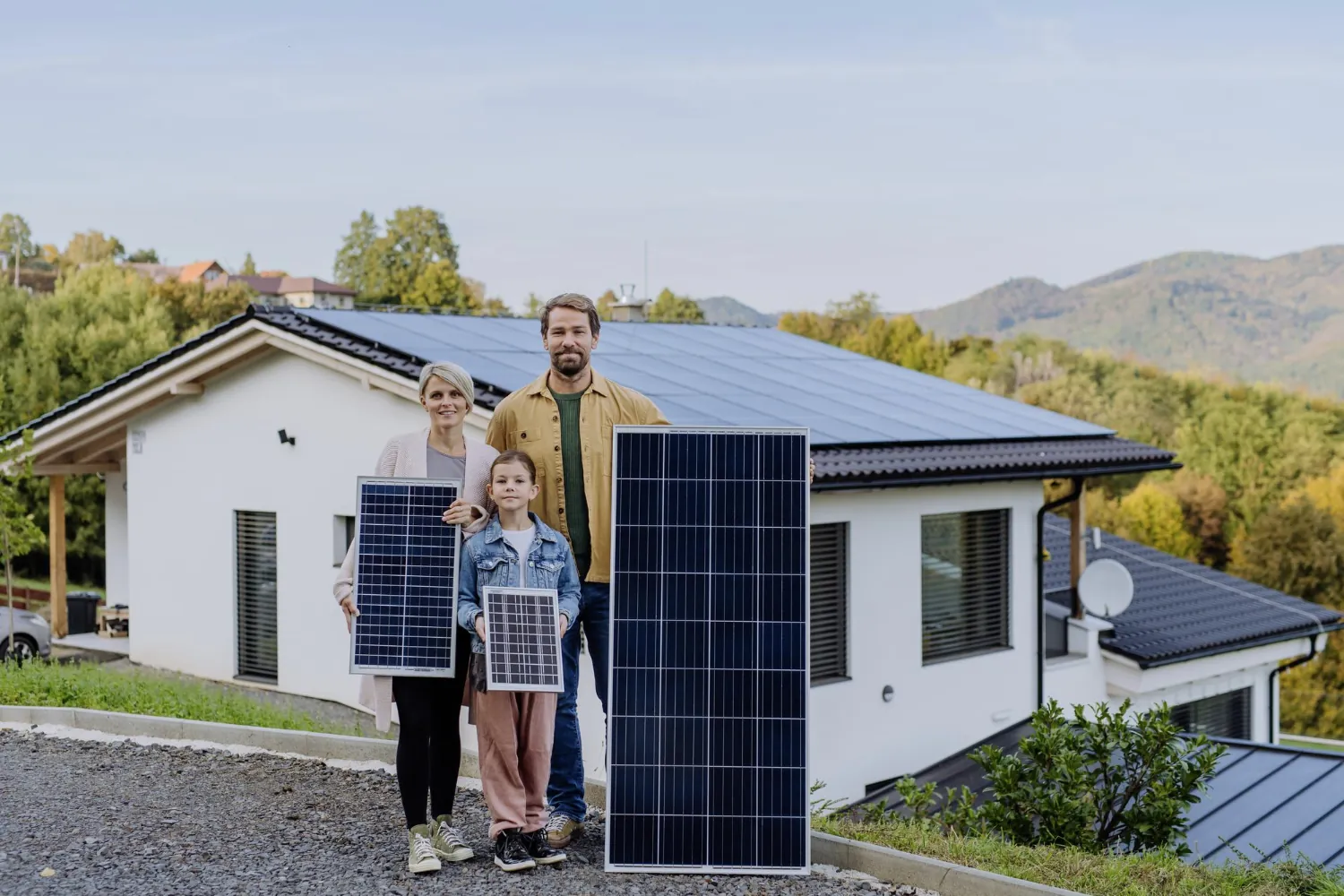 Familie präsentiert hochwertiges Solarmodul vor Einfamilienhaus mit Photovoltaikanlage